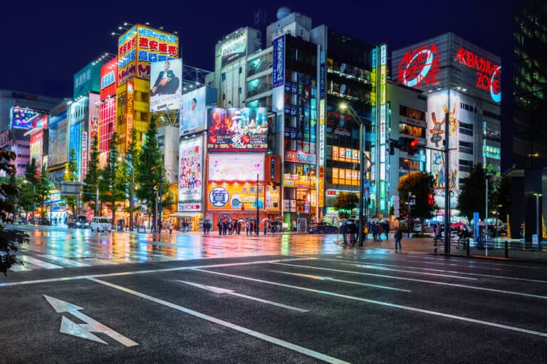 Vibrant Tokyo city street illuminated with neon signs and digital billboards at night.