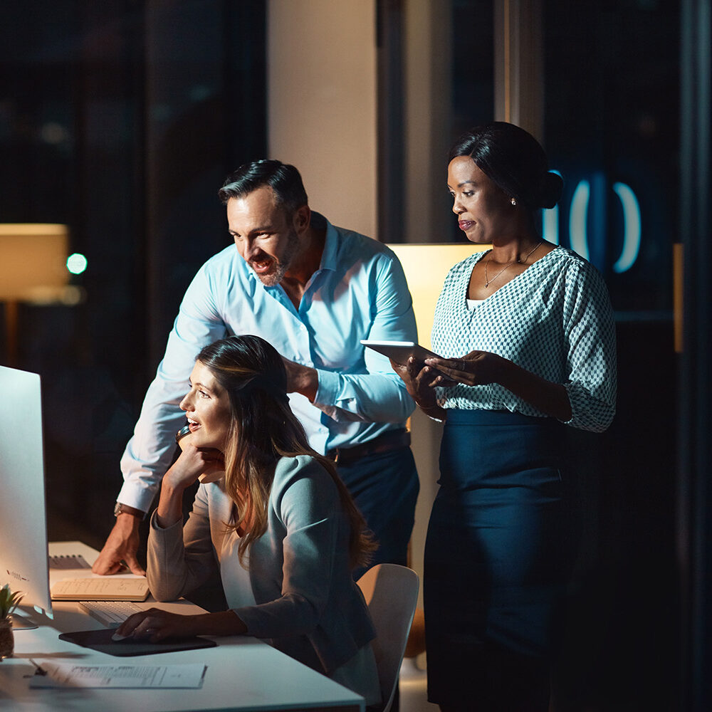 Collaborative team working on digital marketing strategy at night in modern office.